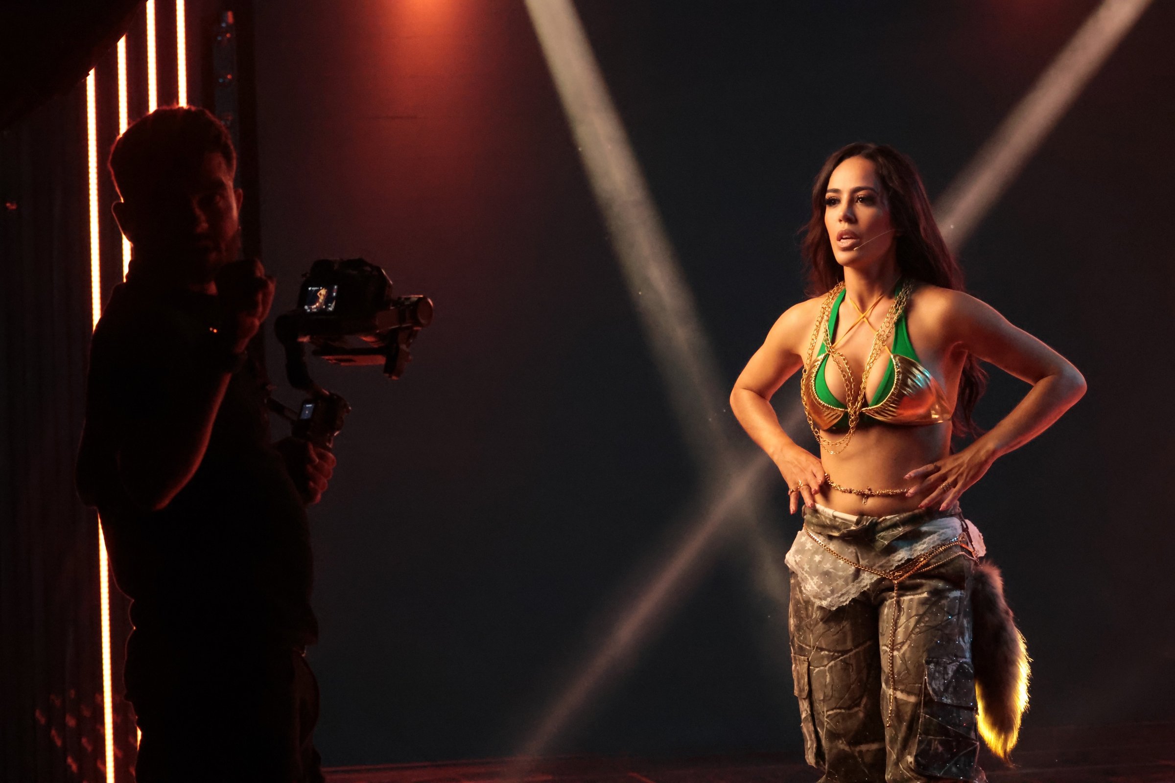 Angel B performing on stage while a camera operator films